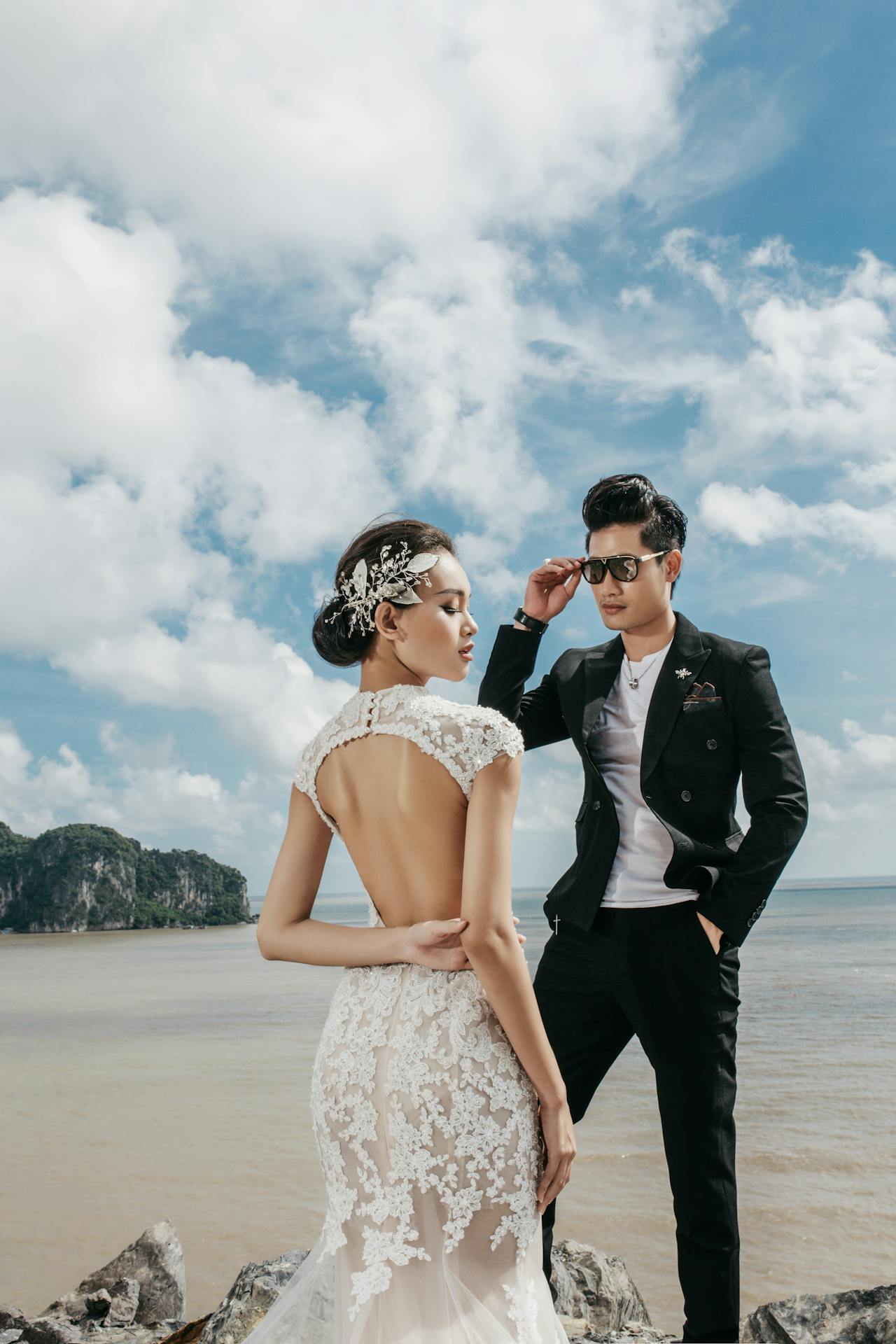 bride and groom standing on rocks at the beach bride and groom standing on rocks at the beach