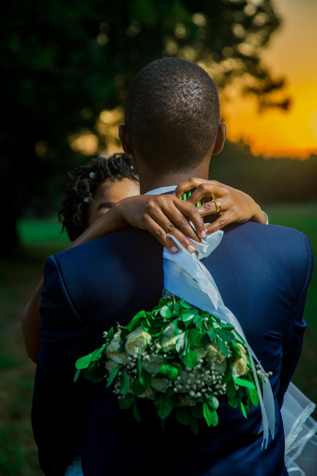 bride and groom bride holding bouqet with ehr arms around grooms neck bride and groom. bride holding bouqet with her arms around mans neck
